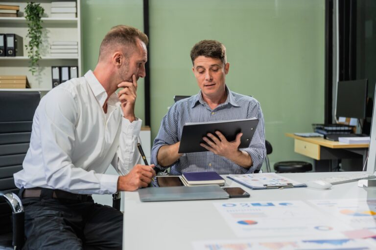 Caucasian middle-aged male businessperson an Italian accountant are seated at a desk, engaging